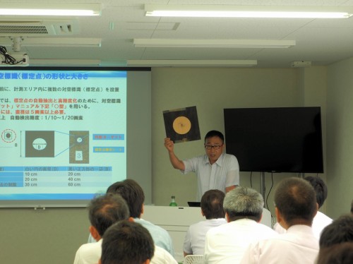 神戸トレーニングセンタで開催された「i-Construction UAV写真測量講習会」。ドローンによる空撮用の対空標識を掲げて説明する講師の大谷仁志さん